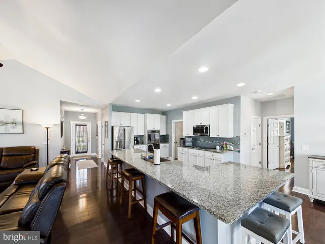 a kitchen with stainless steel appliances granite countertop a stove top oven a sink a dining table and chairs with wooden floor