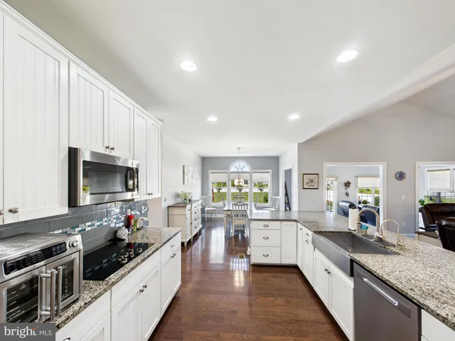 a large kitchen with stainless steel appliances granite countertop a lot of counter space and wooden floors