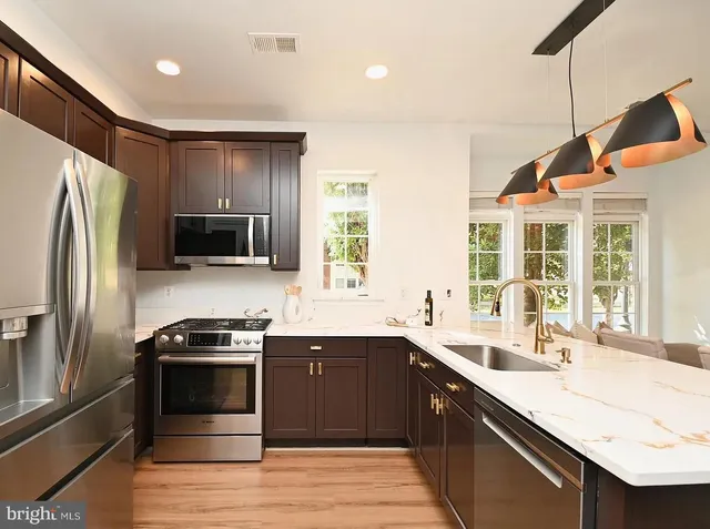 a kitchen with stainless steel appliances granite countertop a sink a stove and refrigerator