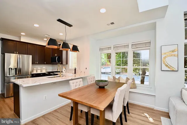 a kitchen with stainless steel appliances granite countertop a stove a refrigerator a sink dishwasher a dining table and chairs with wooden floor