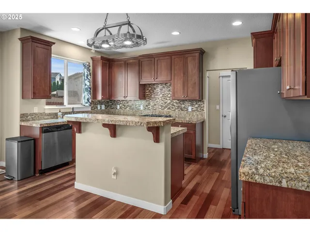 a kitchen with kitchen island granite countertop wooden floors and white cabinets