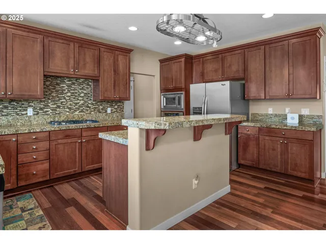a kitchen with kitchen island granite countertop wooden cabinets a refrigerator and a sink