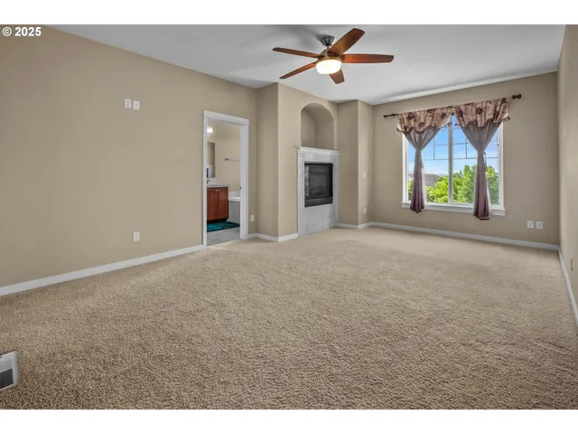 a view of empty room with windows and ceiling fan