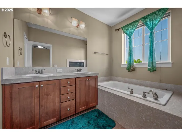 a bathroom with a tub a sink and a large mirror