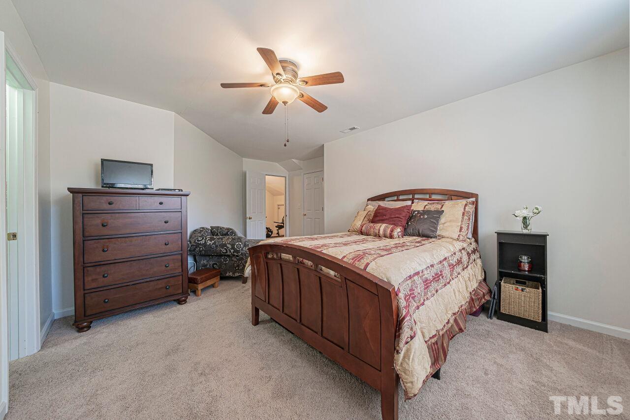 6901 Brigmore Court Raleigh, NC 27617 - Photo 22 of 25 a bedroom with a bed and a chandelier