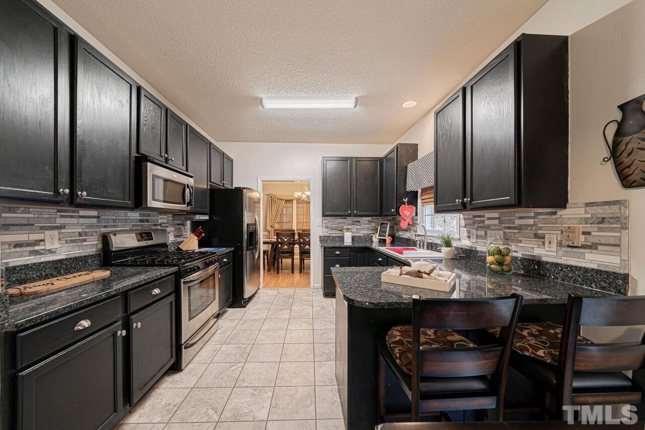 6901 Brigmore Court Raleigh, NC 27617 - Photo 9 of 25 a kitchen with stainless steel appliances granite countertop wooden cabinets a stove top oven a sink and dishwasher