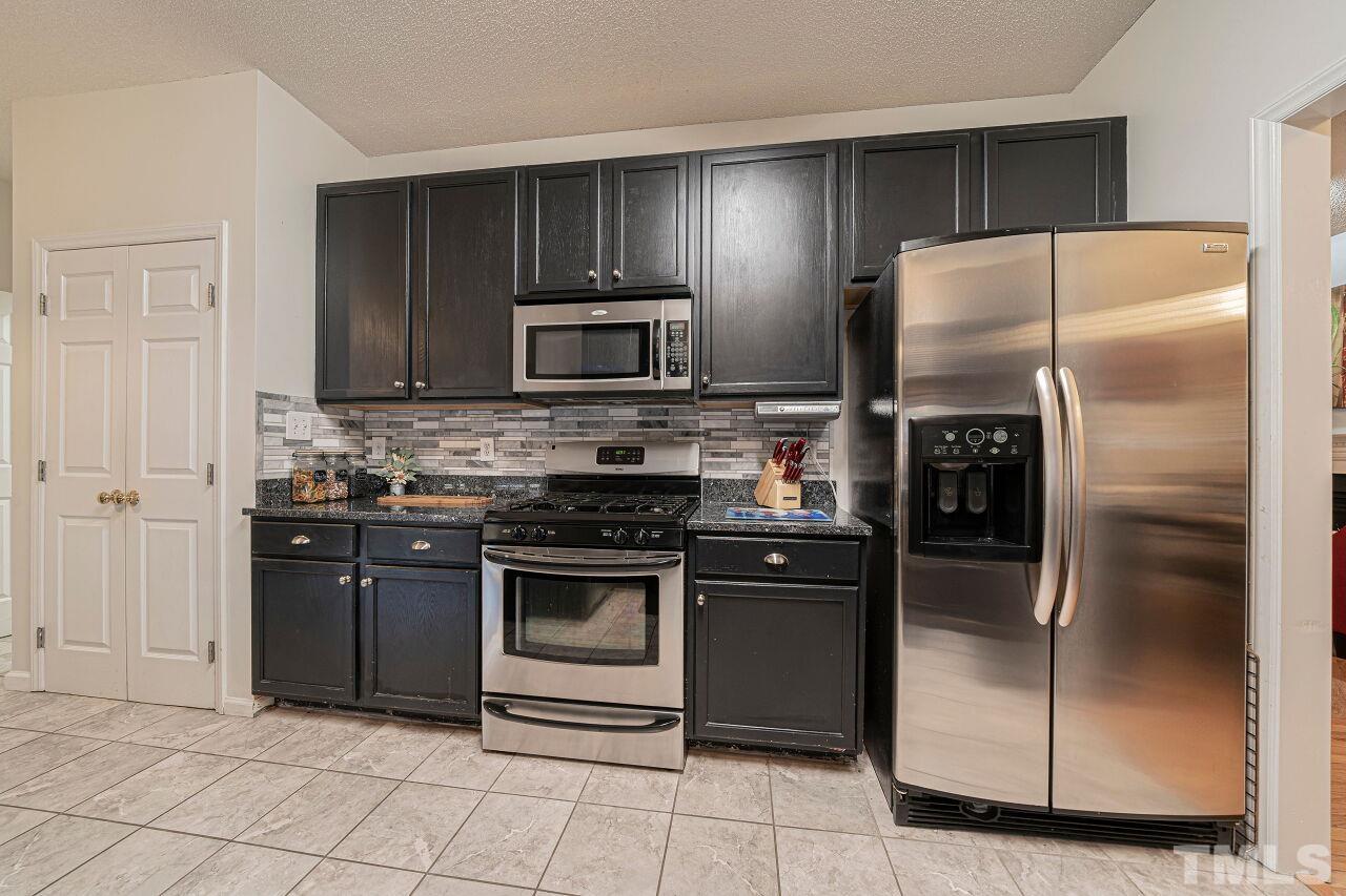 6901 Brigmore Court Raleigh, NC 27617 - Photo 10 of 25 a kitchen with granite countertop a refrigerator and a stove top oven
