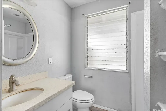 a bathroom with a granite countertop sink toilet a mirror and a tub