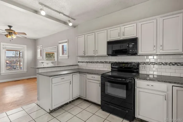 a kitchen with granite countertop white cabinets stainless steel appliances and a sink