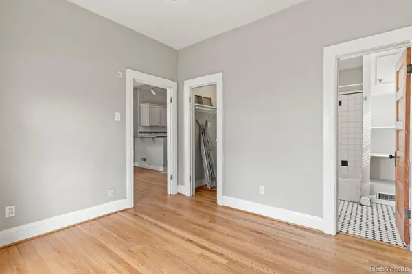 a view of an empty room with wooden floor and a bathroom