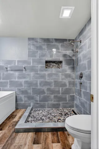 a view of a hallway with wooden floor and a bathroom