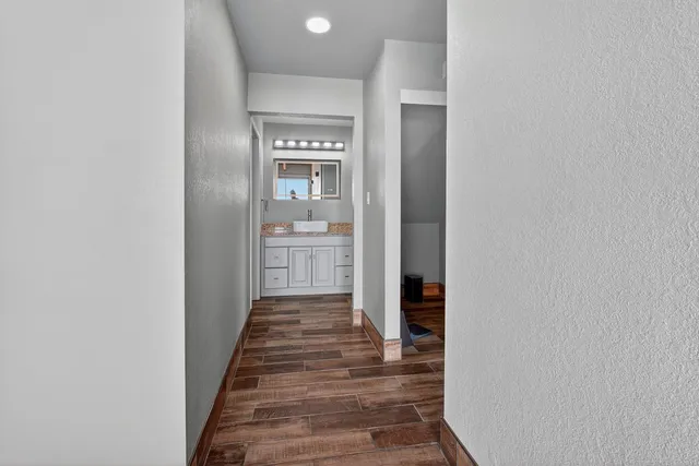 a kitchen with stainless steel appliances a stove a refrigerator a sink and white cabinets with wooden floor