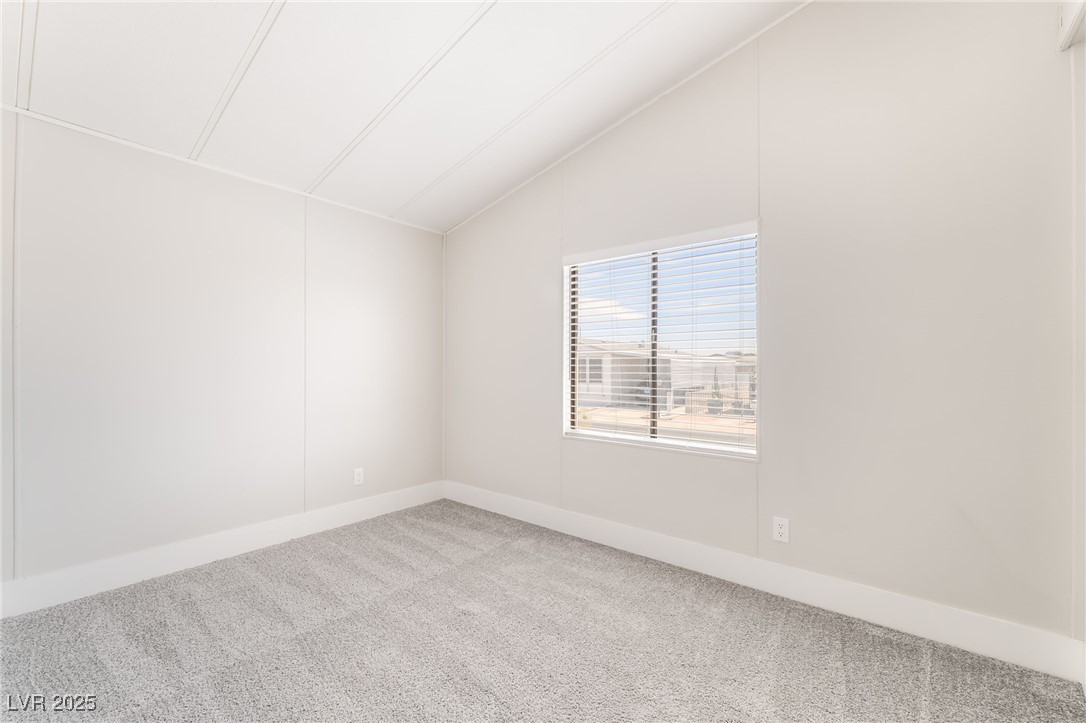 5552 Aldama Road Las Vegas, NV 89122 - Photo 26 of 35 Carpeted empty room featuring vaulted ceiling and baseboards
