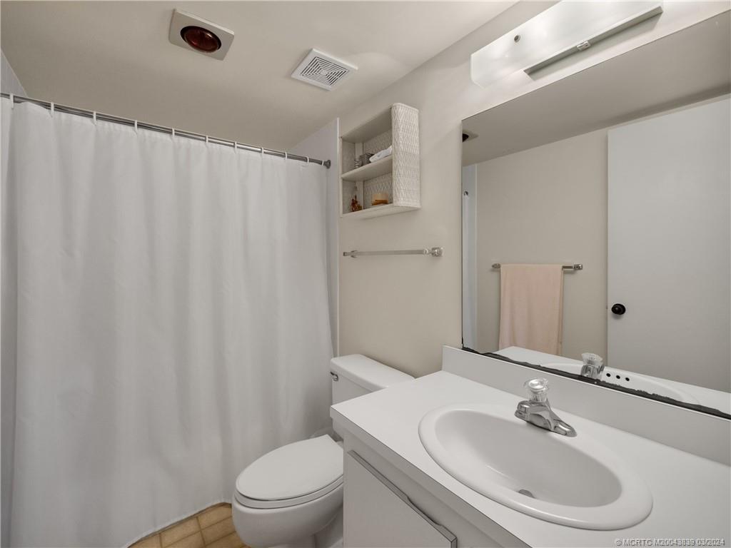 484 Northeast Plantation Road, Unit 4106 Jensen Beach, FL 34957 - Photo 12 of 15 a bathroom with a sink a toilet and shower curtain