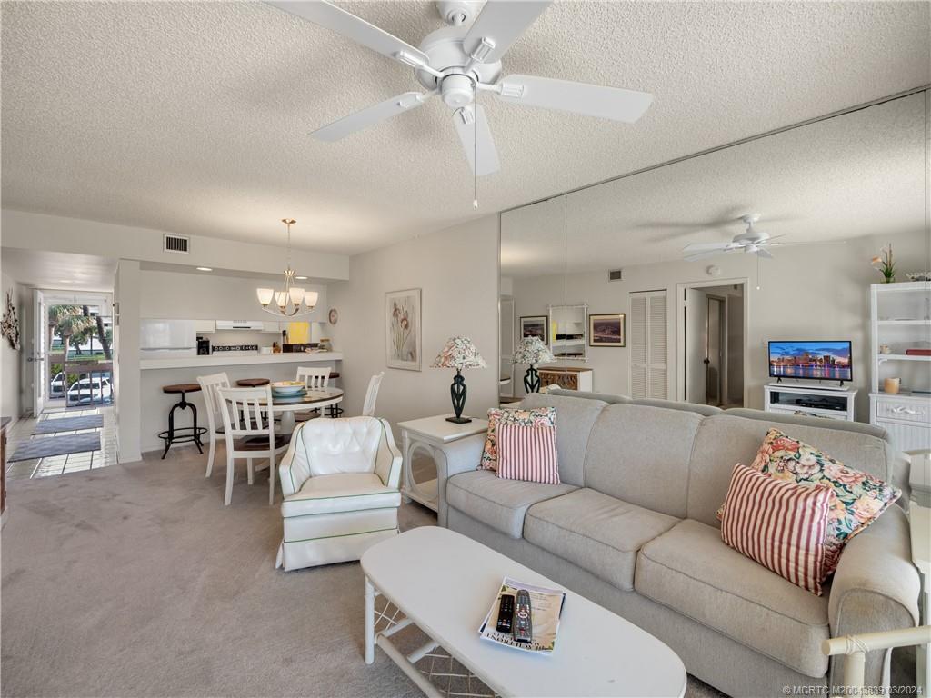 484 Northeast Plantation Road, Unit 4106 Jensen Beach, FL 34957 - Photo 4 of 15 a living room with furniture and a dining table with kitchen view