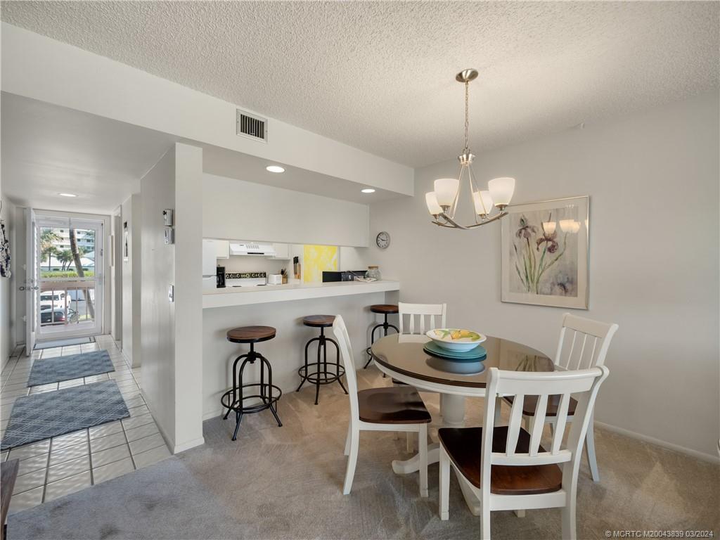 484 Northeast Plantation Road, Unit 4106 Jensen Beach, FL 34957 - Photo 6 of 15 a view of a dining room with furniture wooden floor and a chandelier