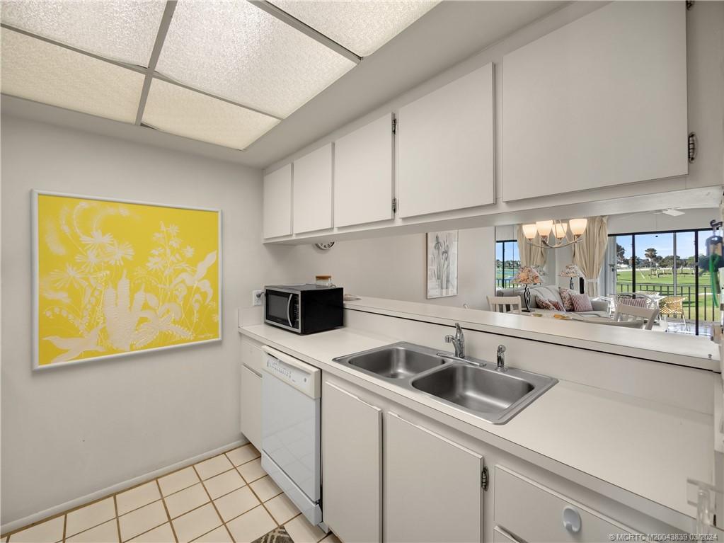 484 Northeast Plantation Road, Unit 4106 Jensen Beach, FL 34957 - Photo 7 of 15 a kitchen that has a sink and white cabinets