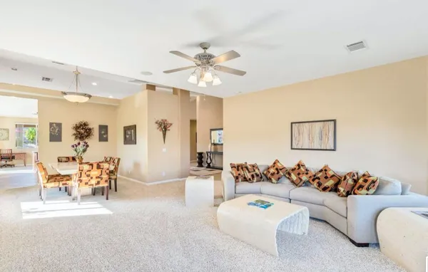 a living room with lots of furniture kitchen view and a large window