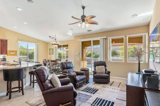 a kitchen with stainless steel appliances kitchen island granite countertop a dining table chairs and a refrigerator