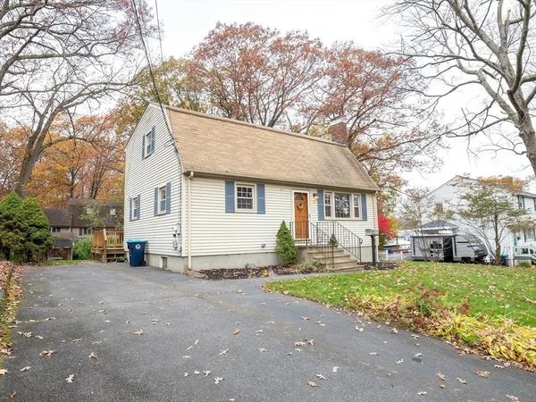 a view of a white house next to a yard and road