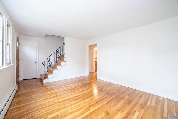 a view of an empty room with wooden floor and stairs