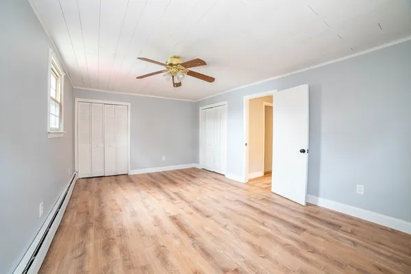 a view of empty room with wooden floor and fan