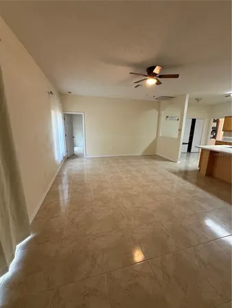 an empty room with a chandelier fan and windows