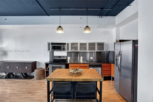 a kitchen with stainless steel appliances kitchen island a table and chairs in it