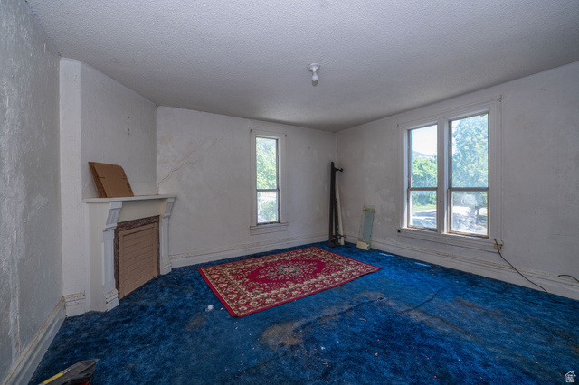 1256 24th Street Ogden, UT 84401 - Photo 18 of 34 Interior space featuring a decorative fireplace mantel, two large windows, a single smaller window, and a ceiling-mounted light fixture