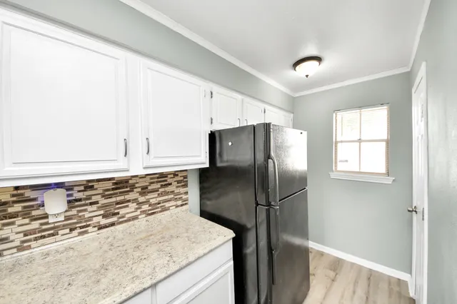 a kitchen with stainless steel appliances granite countertop a refrigerator a sink and white cabinets