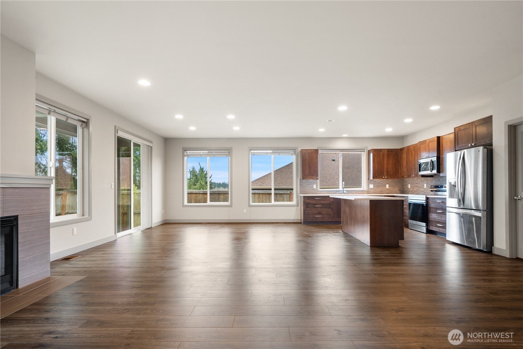 200 Blue Glacier Loop Sequim, WA 98382 - Photo 12 of 39 a view of an empty room with wooden floor and a kitchen