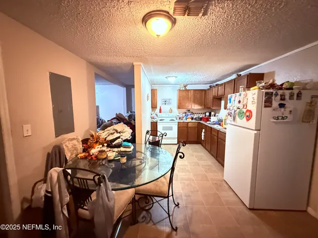 a kitchen with stainless steel appliances kitchen island granite countertop a table chairs and a refrigerator