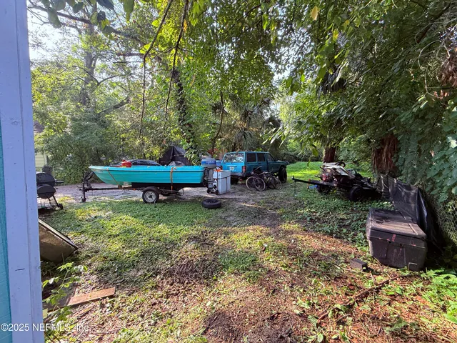 a view of a backyard with table and chairs potted plants and a large tree
