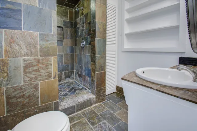 a bathroom with a granite countertop sink a toilet and shower