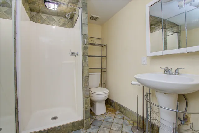 a bathroom with a sink a toilet and shower