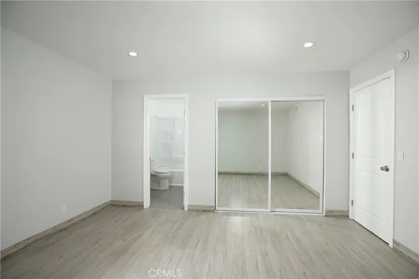 a view of an empty room with wooden floor and closet