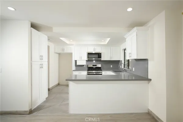 a large kitchen with stainless steel appliances granite countertop a stove a sink and a refrigerator