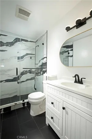 a bathroom with a granite countertop toilet sink and mirror