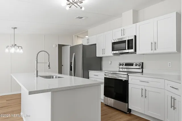 a kitchen with granite countertop a sink and white cabinets