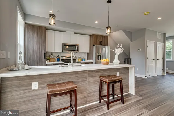a kitchen with stainless steel appliances granite countertop a sink a stove a refrigerator and island with wooden floor