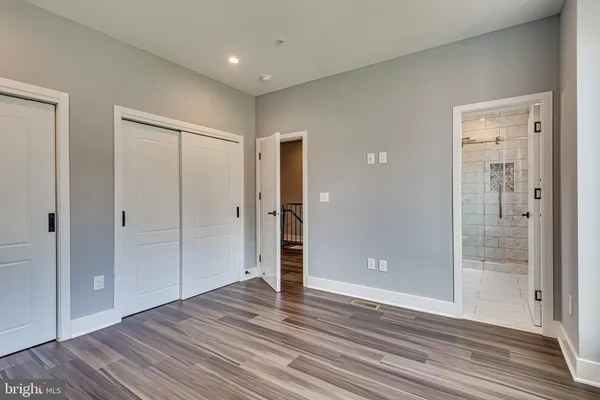 a view of an empty room with wooden floor and mirror