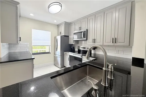 a kitchen with stainless steel appliances granite countertop a sink refrigerator and microwave