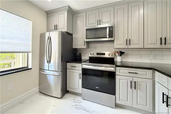 a kitchen with stainless steel appliances white cabinets white stove a microwave and a refrigerator