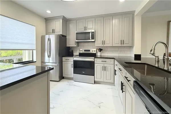 a kitchen with stainless steel appliances granite countertop a stove a sink dishwasher a refrigerator and a microwave