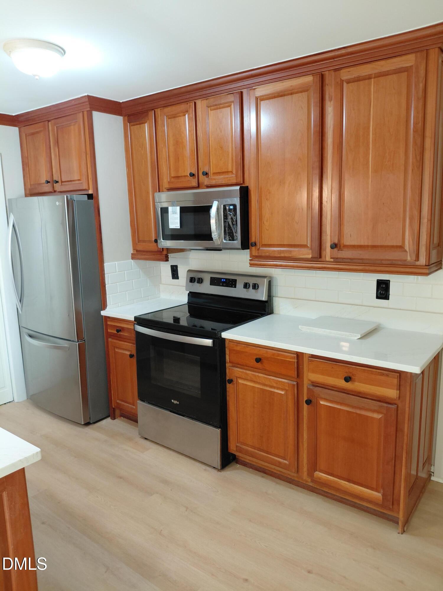 804 Olive Street Apex, NC 27502 - Photo 24 of 60 a kitchen with granite countertop wooden cabinets a stove a refrigerator and a sink