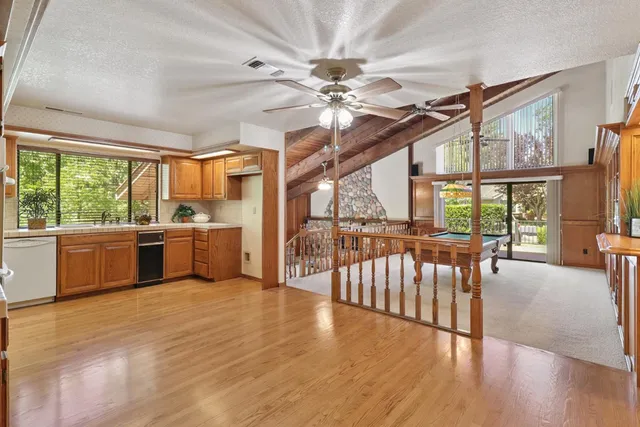 a kitchen with stainless steel appliances kitchen island granite countertop a refrigerator a sink dishwasher a stove and a dining table with wooden floor