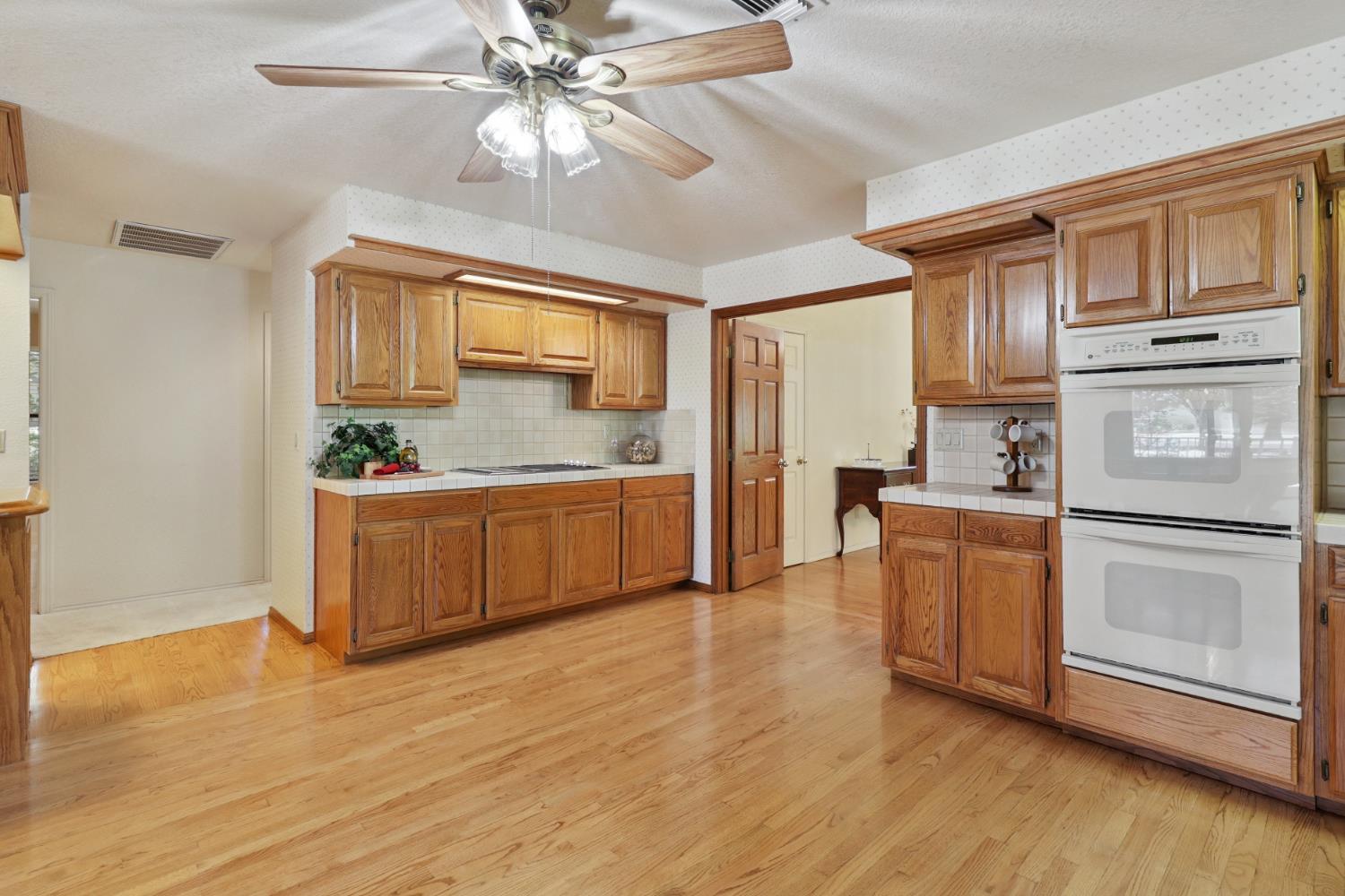 6798 Terreno Drive Rancho Murieta, CA 95683 - Photo 24 of 63 a kitchen with stainless steel appliances granite countertop a refrigerator a stove top oven a chimney wooden floor and cabinets