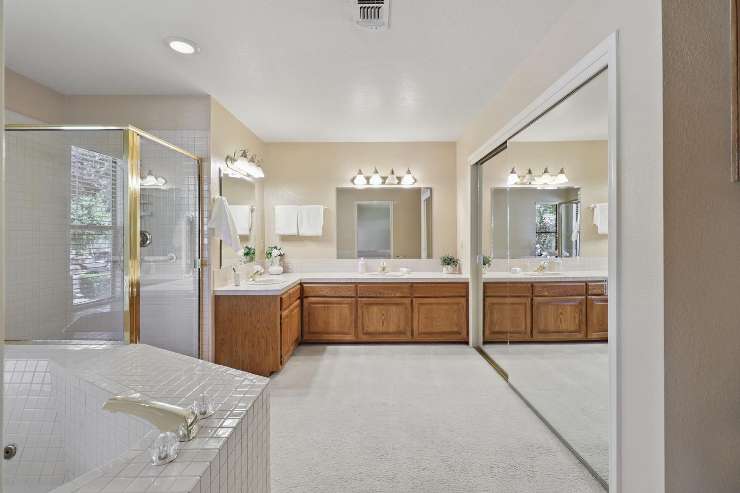 6798 Terreno Drive Rancho Murieta, CA 95683 - Photo 42 of 63 a large bathroom with a large mirror vanity and shower