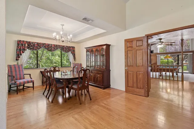 a dining room with furniture a chandelier and wooden floor