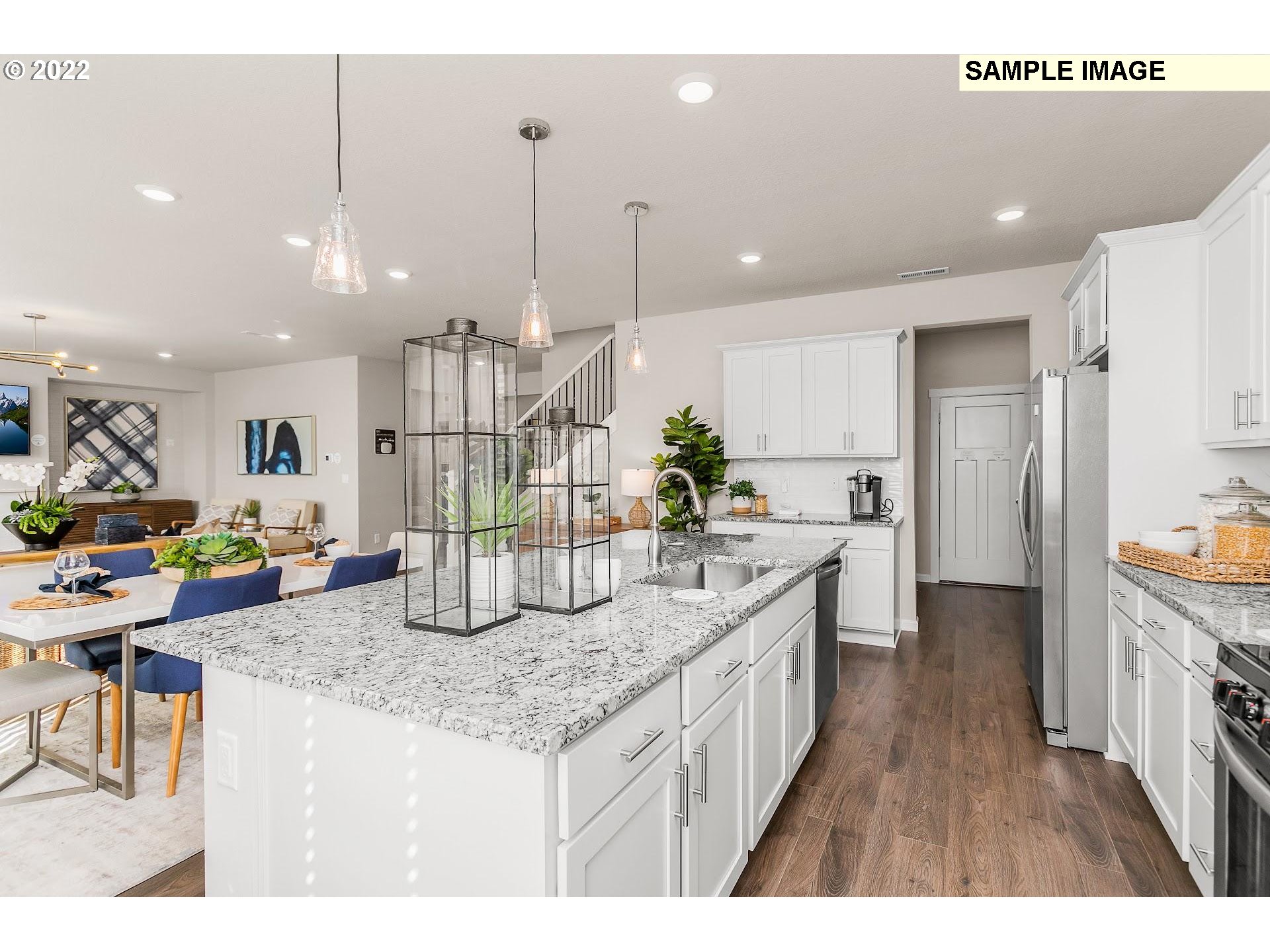 37413 Coho Street Sandy, OR 97055 - Photo 9 of 23 a kitchen with stainless steel appliances kitchen island granite countertop a refrigerator a sink a stove and a wooden floors